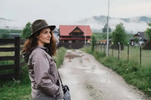 stock image Young woman standing near house in mountain village in summer. Summer trip on mountain routes in Europe.