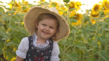 Yazın açan ayçiçeği tarlasında yürüyen küçük bir kız. Mutlu çocuklar yetiştirmek. Ayçiçeği tarlasında kızımla yürüyorum..