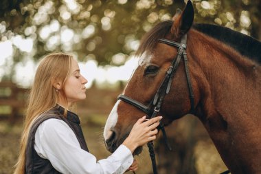 Genç bir dişi binici atının yanında duruyor ve bir yarışa hazırlanıyor. Atlama eğitimini göster. Atları severim..