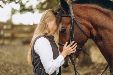 Genç bir dişi binici atının yanında duruyor ve bir yarışa hazırlanıyor. Atlama eğitimini göster. Atları severim..