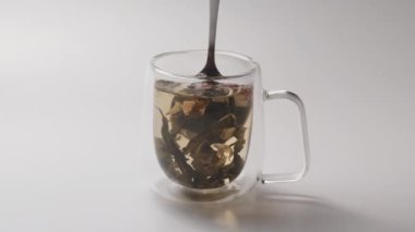 Bir adam çay kaşığıyla beyaz arka planda çay karıştırır. Sağlıklı yeşil çay yapmak.
