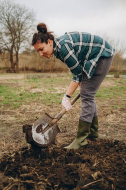 Bir kadın tarlada toprağı kazıyor. İlkbaharda tarımda tarım işi. Baharda koyun ekmek için toprağı hazırlıyorum..