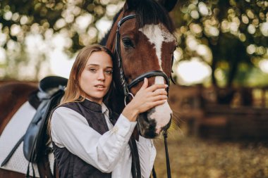 Genç bir dişi binici atının yanında duruyor ve bir yarışa hazırlanıyor. Atlama eğitimini göster. Atları severim..