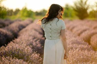 Genç bir esmer yazın günbatımında buğday tarlalarında yürür. Organik buğday ve arpa yetiştiriyor..