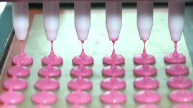 Mat in a Close-up on Production Line, Macaron Factory, Food Factory 'de Pembe Makarna Kabukları' ndan birden fazla makarna ve pembe renkli makarna yapıyorlar. 4K Video çekimi.