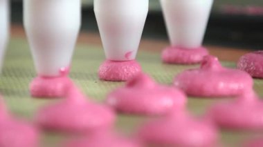 Mat in a Close-up on Production Line, Macaron Factory, Food Factory 'de Pembe Makarna Kabukları' ndan birden fazla makarna ve pembe renkli makarna yapıyorlar. 4K Video çekimi.