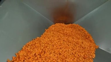 Yiyecek fabrikasındaki üretim hattına koni şeklinde cips dökmek. Sarı baharatlı patates cipsi dokusu ya da mısır konisi arkaplanı. 4K video çekimi.