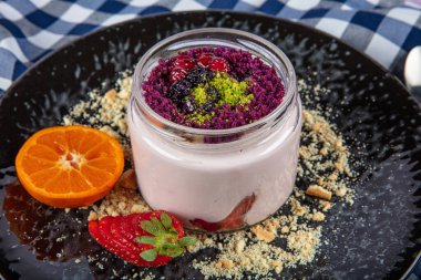 Siyah servis tabağında kremalı ve çilekli çilekli manolya tatlısı. Dünya mutfağı lezzetleri.