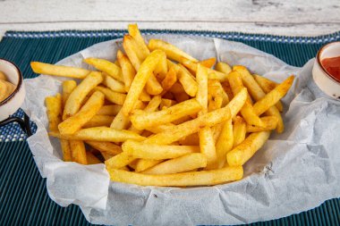 Beyaz ahşap bir tahtanın üzerinde mayonez ve biberiyeli ev yapımı fırında patates kızartması..