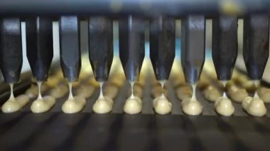 Üretim hattında bir sürü tatlı krema pişiriyor. tatlı yemek konsepti. Yeni pişmiş, çıtır çıtır, dikdörtgen ekler. Geleneksel Fransız ekleriymiş. Kalite 4K video yakalama.