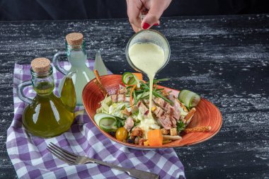 Dünya mutfağı tavuk salatası. Koyu mutfak masasında fırında tavuk göğsü ile yeşil salata. Sağlıklı yiyecekler, temiz yeme konsepti. 