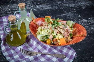 Dünya mutfağı tavuk salatası. Koyu mutfak masasında fırında tavuk göğsü ile yeşil salata. Sağlıklı yiyecekler, temiz yeme konsepti. 