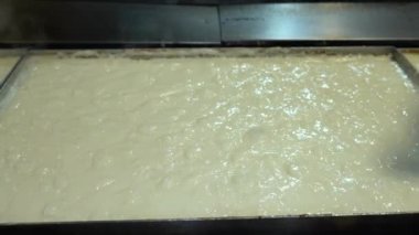 Geleneksel Türk mutfağı Tatlı Kazandibi (Kızarmış Puding). Yerel adı: Kazandibi. Bir gıda fabrikası 4K video çekiminde kavrulmuş puding üretim süreci.