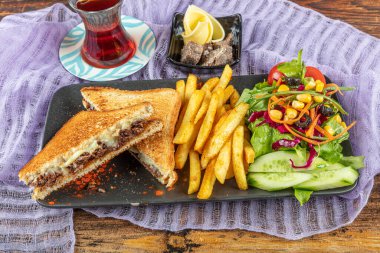 Çedar peynirli kulüp tostu. Eritilmiş peynirli tost sandviçi ve kızarmış et. Kızarmış et, tost ve salata ile servis edilir..