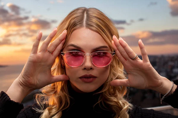 stock image Beautiful female model wearing colorful glasses at sunset. Outdoors romantic portrait of attractive blonde woman with makeup and glasses posing. Istanbul archipelago (Princess Islands) skyline.