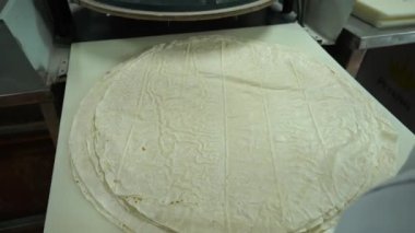 Food Factory otomatikman fillo hamur üretiyor. Hamur taşıyıcı, fillo ekmeği pişirme işlemi. 4K kalite video çekimi. Geleneksel, fillo hamuru (buğday unundan yapılır). yerel isim; Yufka.