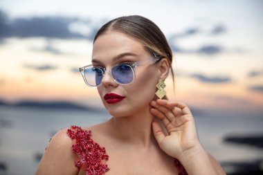 Gün batımında renkli gözlük takan güzel bir kadın model. Açık havada, makyajlı ve gözlüklü çekici sarışın bir kadının romantik portresi. İstanbul takımadaları (Prenses Adaları) ufuk çizgisi.