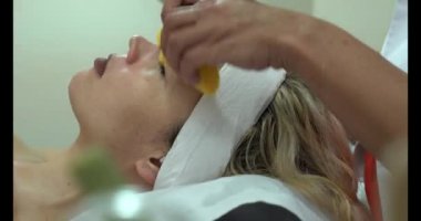 Kozmetik kliniğindeki genç bir kadının parlak yüz derisi. Modern insanlar için profesyonel nemlendirici, gençleştirici donanım prosedürleri. Güzel bir kadın kaplıcada uzanıyor ve yüz bakımı yaptırıyor..