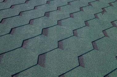 Kalçalı bir evin çatısındaki yeşil yumuşak ziftlerden yapılmış çatı. Asfalt Çatısı Yeşil Döşeme Arkaplanı 'nın yakın görüntüsü. Evin çatısında yeşil fayanslar var. Çatı Kiremitleri, Çatı Tamiri.