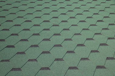 Kalçalı bir evin çatısındaki yeşil yumuşak ziftlerden yapılmış çatı. Asfalt Çatısı Yeşil Döşeme Arkaplanı 'nın yakın görüntüsü. Evin çatısında yeşil fayanslar var. Çatı Kiremitleri, Çatı Tamiri.