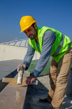 İnşaatçı çekiçle misketi vuruyor ve ruh seviyesiyle dengeliyor. Usta cilalı mermer korkulukları değiştirir..