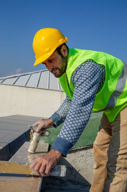 İnşaatçı çekiçle misketi vuruyor ve ruh seviyesiyle dengeliyor. Usta cilalı mermer korkulukları değiştirir..
