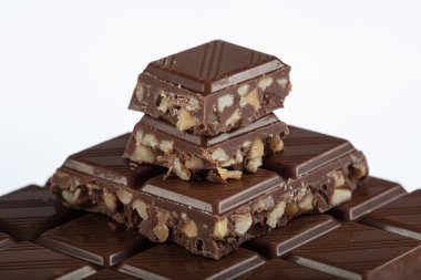 Fındıklı çikolata. Fındıklı çikolata parçaları kulesi. Süt ve siyah çikolata bir arada duruyor. Beyaz arka planda fındıklı sütlü çikolata