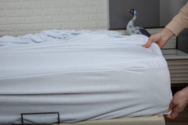 Corner of the sheet with sewn-in elastic band for a good fit on the mattress and a comfortable sleep. White fabric for mockup overlay design. Home textiles for the bedroom. Bedspread mattress.