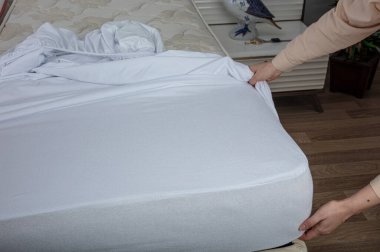 Corner of the sheet with sewn-in elastic band for a good fit on the mattress and a comfortable sleep. White fabric for mockup overlay design. Home textiles for the bedroom. Bedspread mattress.