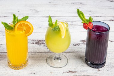 Pomegranate juice lemonade and orange juice served on a wooden serving tray on a wooden table.