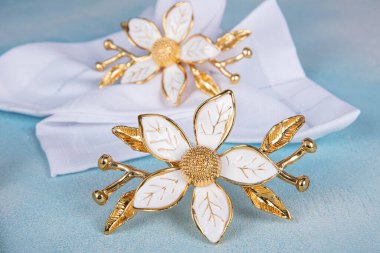 Napkins beige restaurant with holder ring metallic luxury decor. Iron napkin holder with floral pattern. Napkin close-up in the napkin holder.