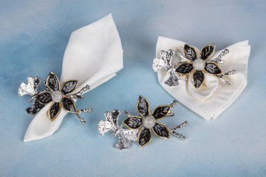 Napkins beige restaurant with holder ring metallic luxury decor. Iron napkin holder with floral pattern. Napkin close-up in the napkin holder.