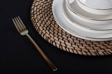 Plates and utensils, Plate, Bowl and golden cutlery against dining table background, side view. Modern craft ceramic tableware.