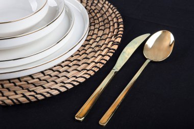 Plates and utensils, Plate, Bowl and golden cutlery against dining table background, side view. Modern craft ceramic tableware.