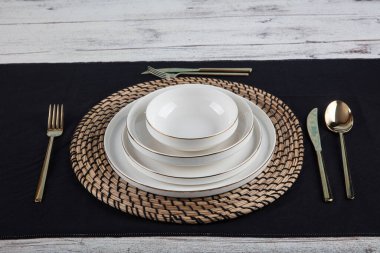 Plates and utensils, Plate, Bowl and golden cutlery against dining table background, side view. Modern craft ceramic tableware.