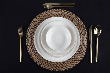 Plates and utensils, Plate, Bowl and golden cutlery against dining table background, side view. Modern craft ceramic tableware.