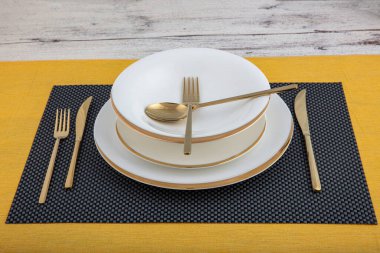 Plates and utensils, Plate, Bowl and golden cutlery against dining table background, side view. Modern craft ceramic tableware.