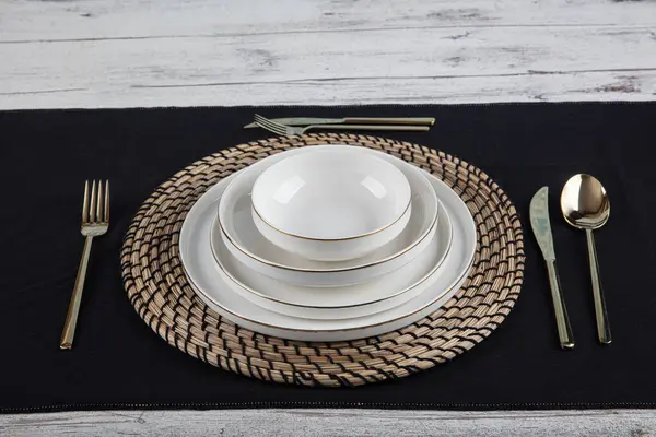 Plates and utensils, Plate, Bowl and golden cutlery against dining table background, side view. Modern craft ceramic tableware.