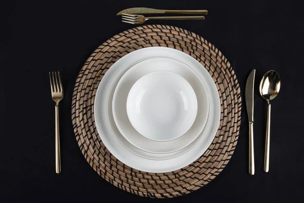 Plates and utensils, Plate, Bowl and golden cutlery against dining table background, side view. Modern craft ceramic tableware.