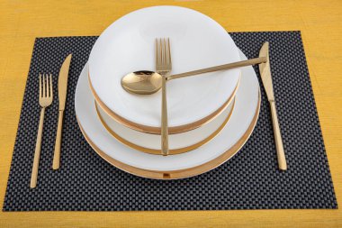 Tabaklar ve kaplar, tabak, kase ve yemek masasında altın çatal bıçak takımı, yan görüş. Modern zanaat seramik sofra takımı, yemek masasında çatal bıçak takımı..
