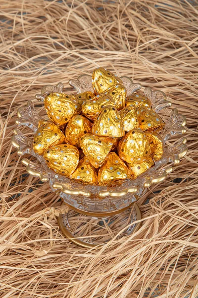 Chocolates wrapped in foil in luxury candy. Chocolate candies in a box in a gold wrapper.