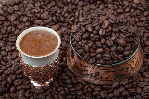 Turkish coffee concept, cup of coffee with coffee beans on coffee bean background. Turkish coffee in a copper cup.