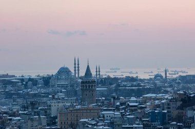 İstanbul, Türkiye 'deki Galata Kulesi. Altın saat havası ve güzel güneş ışığı manzarası. İstanbul Süleyman Camii ve Galata Kulesi 'nde kar ve kış mevsimi manzarası.