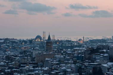 İstanbul, Türkiye 'deki Galata Kulesi. Altın saat havası ve güzel güneş ışığı manzarası. İstanbul Süleyman Camii ve Galata Kulesi 'nde kar ve kış mevsimi manzarası.