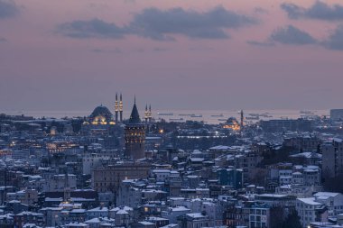 İstanbul, Türkiye 'deki Galata Kulesi. Altın saat havası ve güzel güneş ışığı manzarası. İstanbul Süleyman Camii ve Galata Kulesi 'nde kar ve kış mevsimi manzarası.