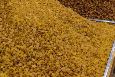 Kuru üzümler bir mağazanın tezgahına ya da markete yığılır. Kurutulmuş meyve. Piyasa tezgahında tohumsuz altın kuru üzümler. 