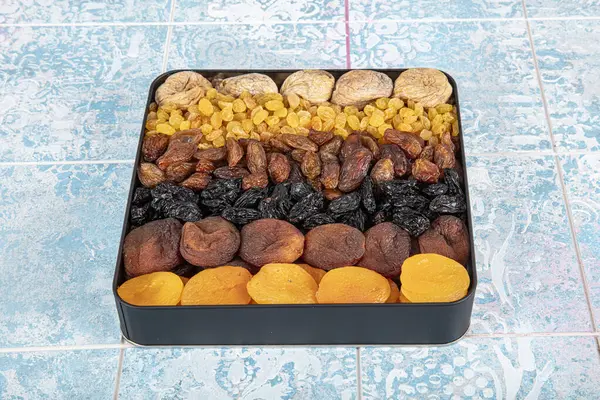 Mixed dried fruits box. Dried fruit background. Rows of dried dates, apricots, raisins, hazelnuts, dried apricots and figs.