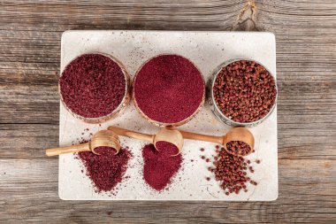 Tahta kaşıkta kuru baharatlı sumak. Yer sumac baharatı. Kurutulmuş kırmızı Sumac tozu, ahşap kaşıkta, kırsal masada sumak üzümlü baharatlar. Sağlıklı gıda konsepti.