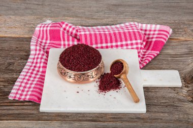 Tahta kaşıkta kuru baharatlı sumak. Yer sumac baharatı. Kurutulmuş kırmızı Sumac tozu, ahşap kaşıkta, kırsal masada sumak üzümlü baharatlar. Sağlıklı gıda konsepti.