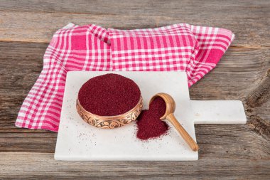 Tahta kaşıkta kuru baharatlı sumak. Yer sumac baharatı. Kurutulmuş kırmızı Sumac tozu, ahşap kaşıkta, kırsal masada sumak üzümlü baharatlar. Sağlıklı gıda konsepti.